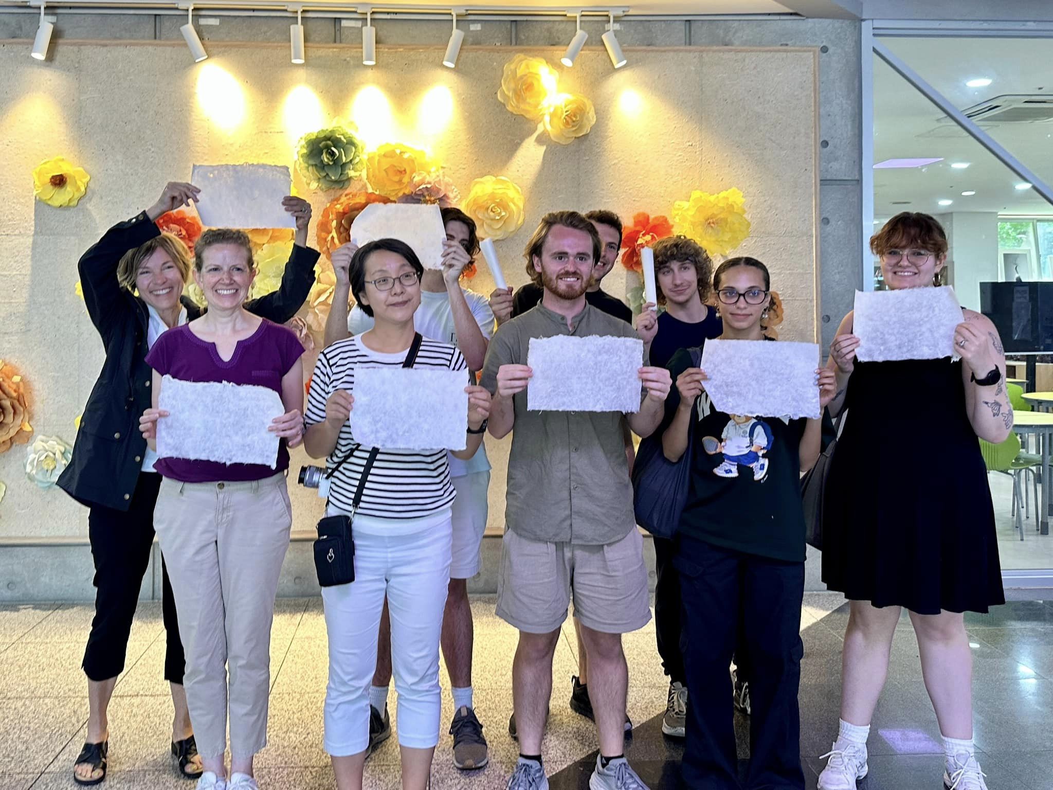 Seven individuals hold up freshly-made hanji paper